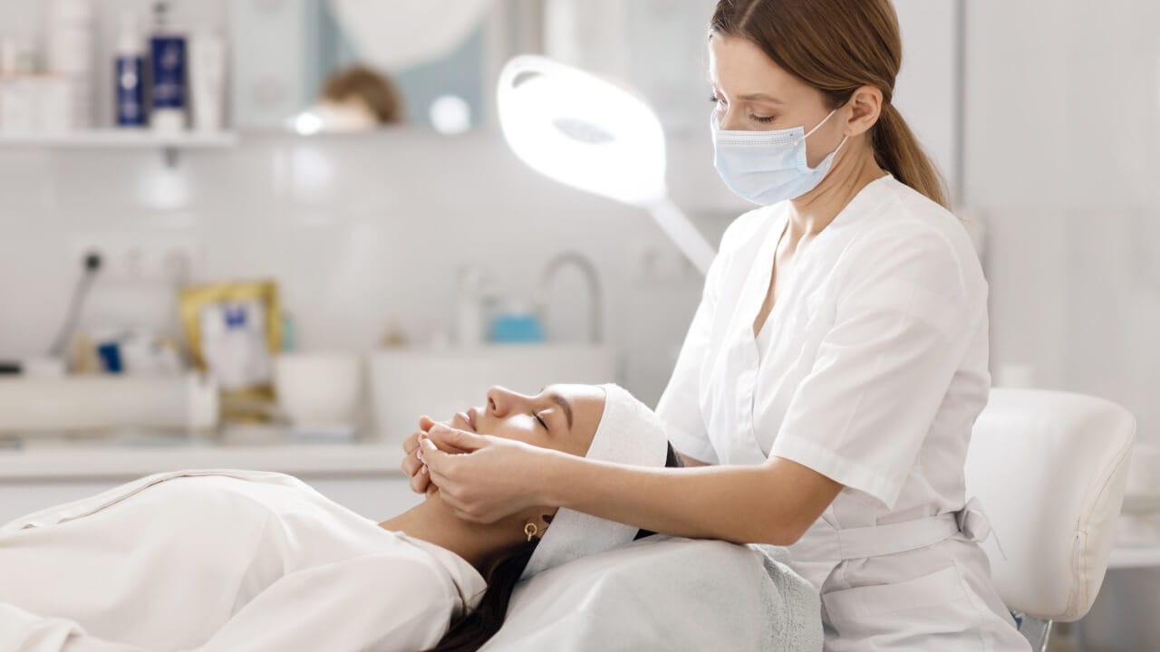 Mulher deitada com profissional fazendo harmonização facial