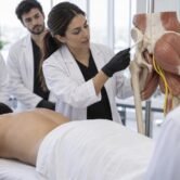 Médica demonstra marcação anatômica da região glútea em aula prática de curso de preenchimento glúteo